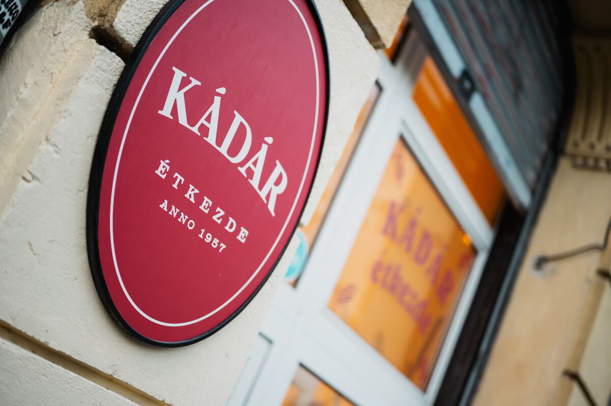 A Kádár Étkezde piros, ovális cégtáblája a bejárat mellett